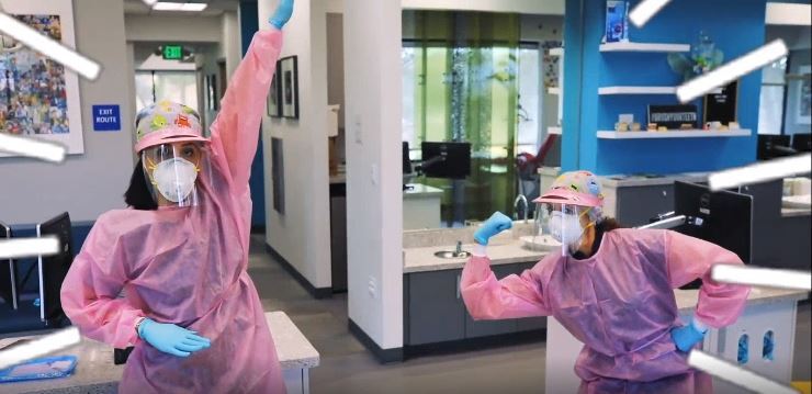 Two people in pink personal protective equipment at a dentist office. 