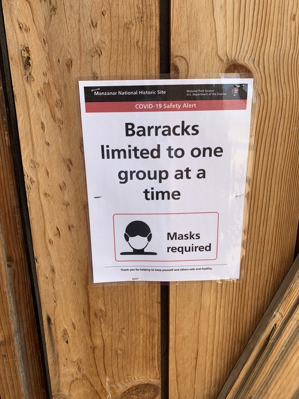 This is a picture taken of a sign that limits the size of groups let into an area, and requires them to wear face masks.