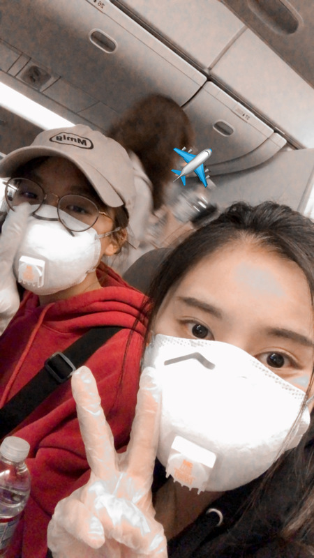 Two people with masks on an airplane. 