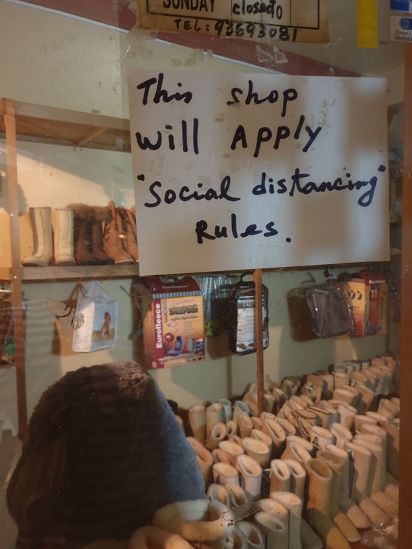 Photo of a sheepskin products shop with a sign on the window that reads, "This shop will apply "social distancing" rules." 