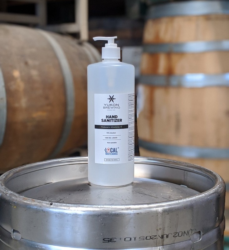 This is a picture of a squirt bottle resting on top of a beer keg which is labeled "Yukon Brewing Hand Sanitizer."