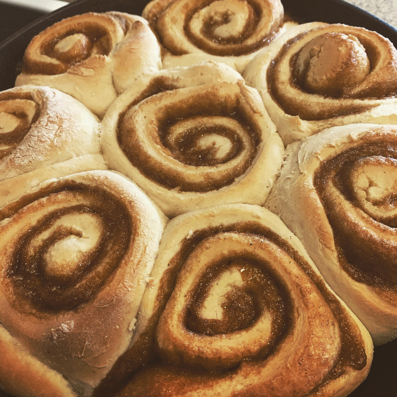 This is a picture of freshly baked cinnamon rolls sitting in a tray. 