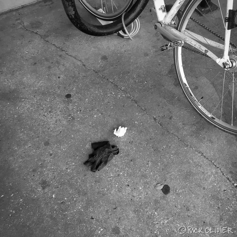 A disposable glove is on the ground near a parked bike. 