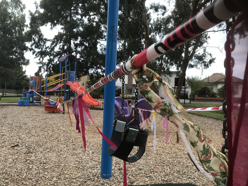 A decorated tape with ribbons tied on it that is sectioning off a playground. 