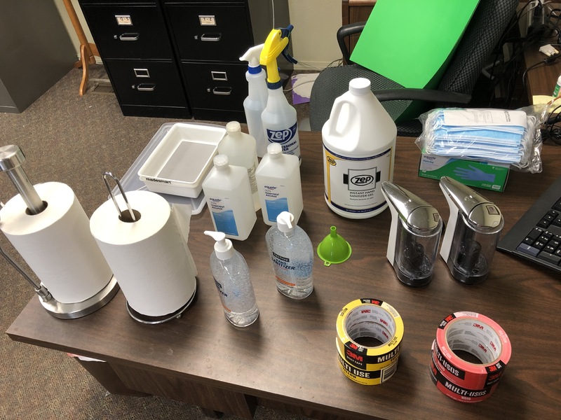A table covered in various cleaning supplies in preparation for reopening.
