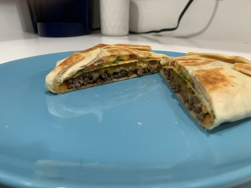 This is a picture taken of a type of grilled quesadilla, with cheese and meat inside. 