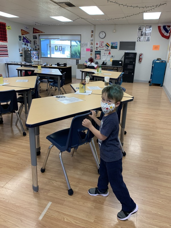 Image of a boy wearing a mask in an empty classroom.