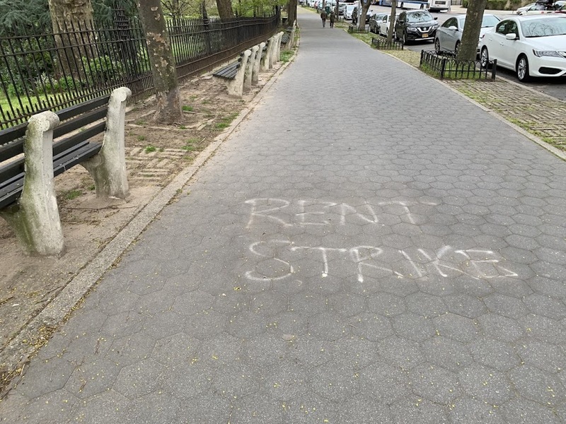 white spray paint on the sidewalk saying "rent strike" 