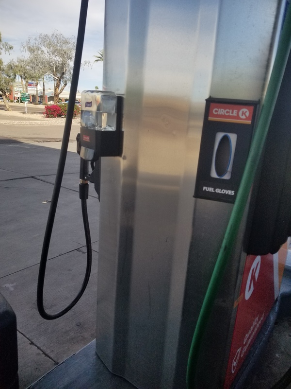 A gas station pump at Circle K that has a hand sanitizer dispenser mounted on the left side with a dispenser for fuel gloves next to it. 