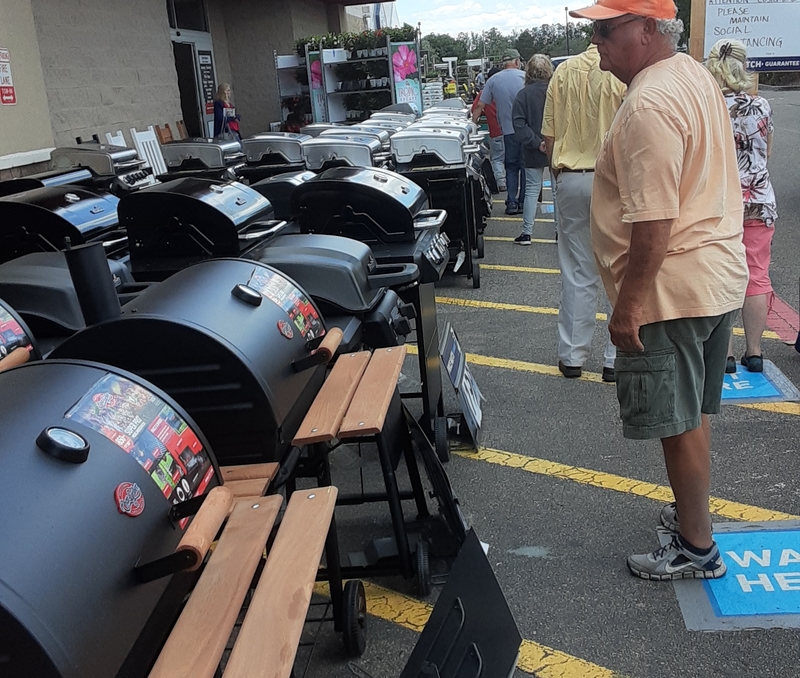 People waiting in line next to grills. 