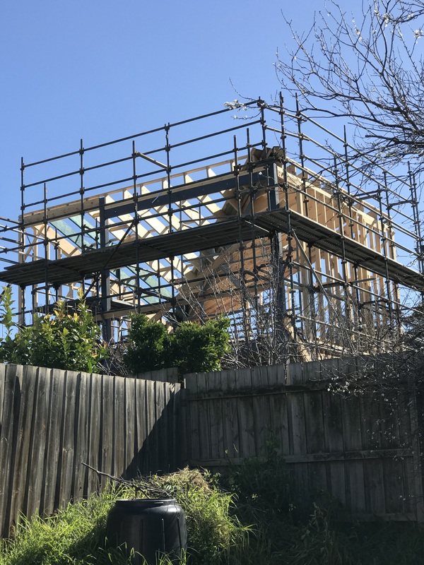 A picture of a house under construction, covered in scaffolding. 