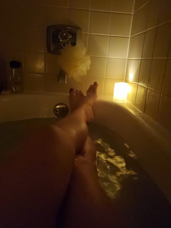 A person's legs in a bathtub. 