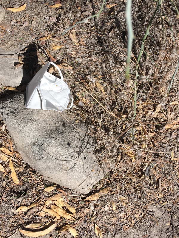 Discarded white mask on the rocky ground.