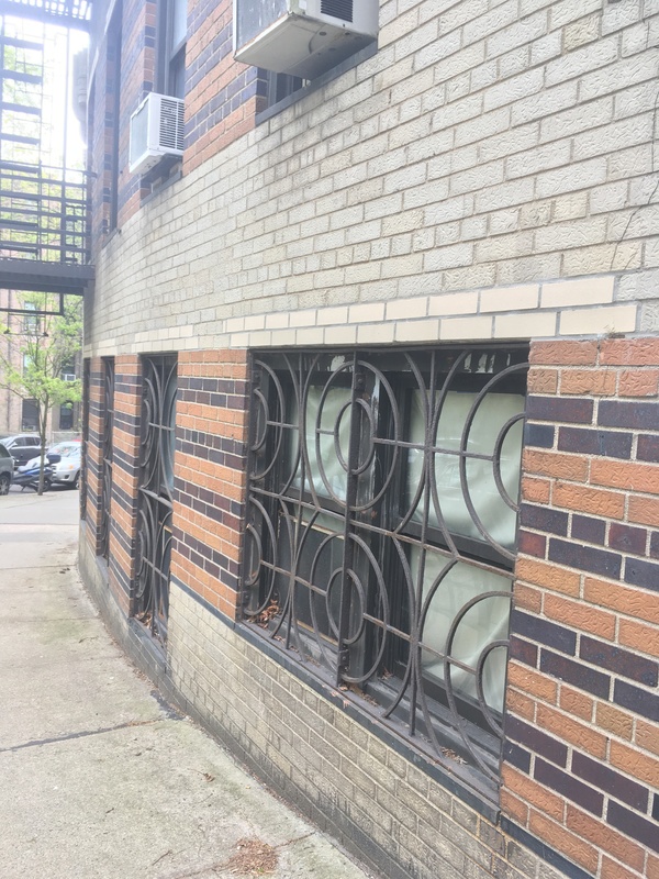 Low windows in a brick building beside a sidewalk.