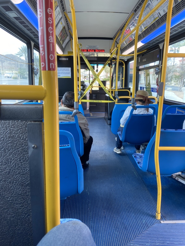 Image of people on a bus with the front of the aisle taped off.