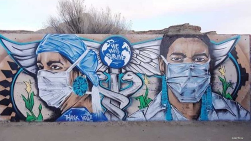 This is a picture of a mural on a wall which depicts two front line medial workers wearing face masks, with a caduceus in between them. The globe on the caduceus has the words "We Will survive" painted on it, and a message on the bottom of the mural reads "Thank you !!". 