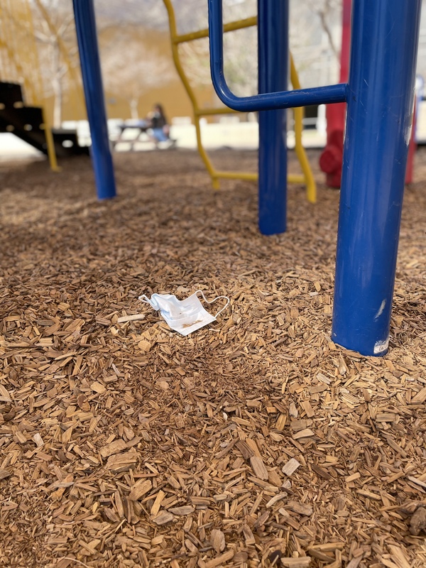 This is a picture of a lost face mask that was left on the ground in a playground. 