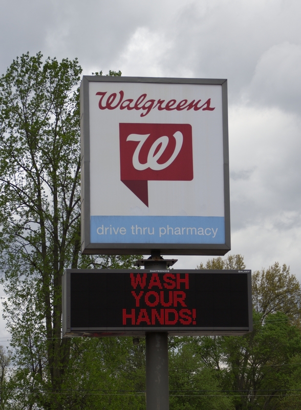 A sign outside a Walgreens reading "wash your hands".