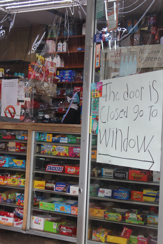 A sign in a store telling people to go to the window instead of the door. 