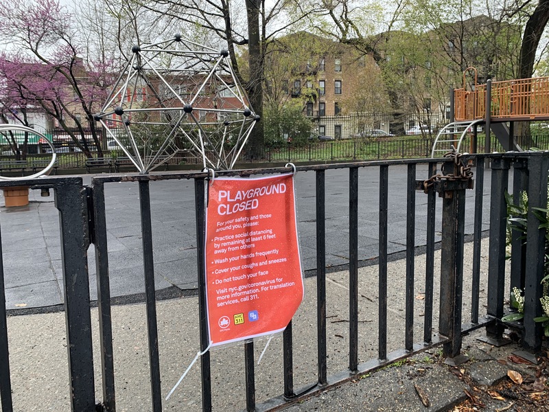 sign tied to a gate stating that a playground is closed due to corona virus 