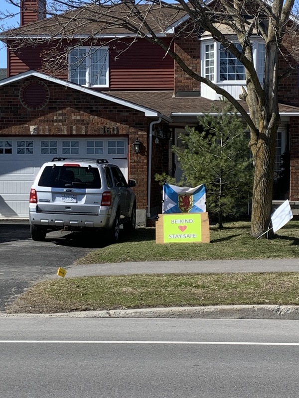 Image of a sign in a front yard which says be kind, stay safe.