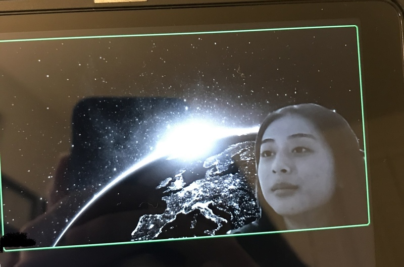 This is a picture of a girl's face superimposed over a background image of the earth from space. 