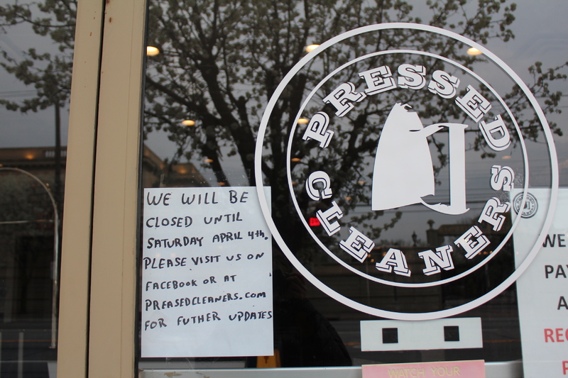 A small handwritten sign at a business called Pressed Cleaners. The sign says: "We will be closed until Saturday April 4th, please visit us on Facebook or at preasedcleaners.com for further updates."