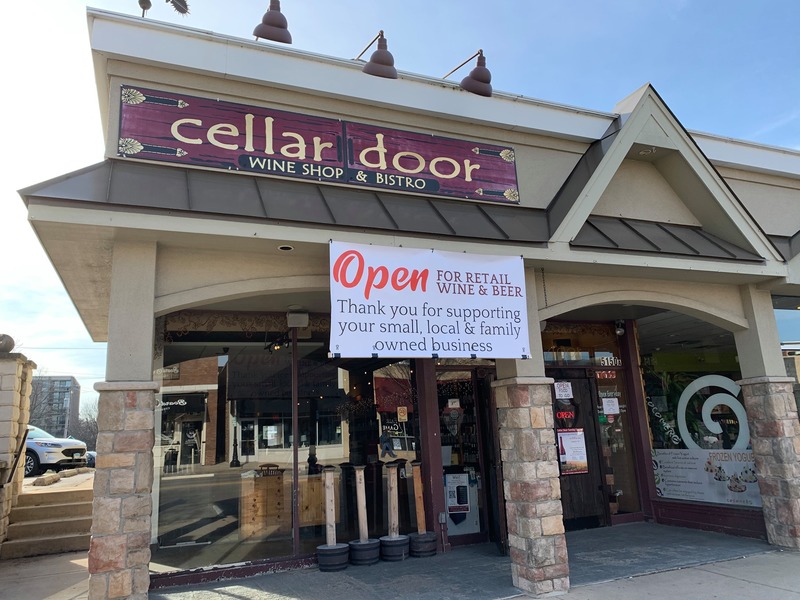 Banner in front of the restaurant Cellar Door Wine Bar & Bistro that says "Open for retail wine and beer. Thank you for supporting your small, local, & family owned businesses." 
