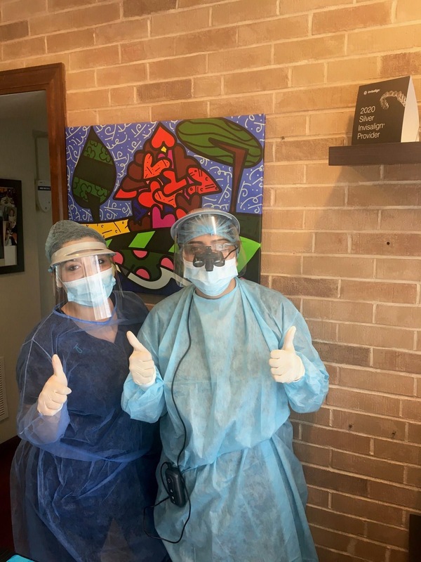 Image of two doctors giving a thumbs up sign while wearing COVID-19 protective face shields, masks, and scrubs. 