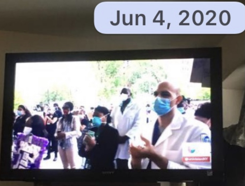 This is a picture taken of a TV screen, which seems to show a group of healthcare workers wearing masks, and applauding. 