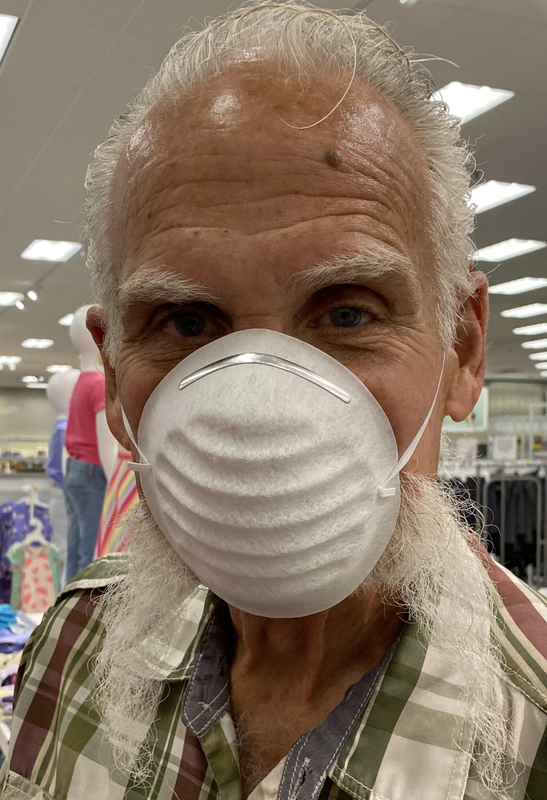 An older man with his beard falling out from a mask.
