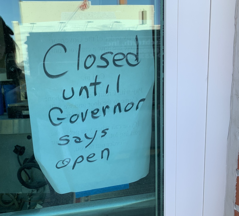 A sign that is taped on the inside of a door that says: "Closed until Governor says open".