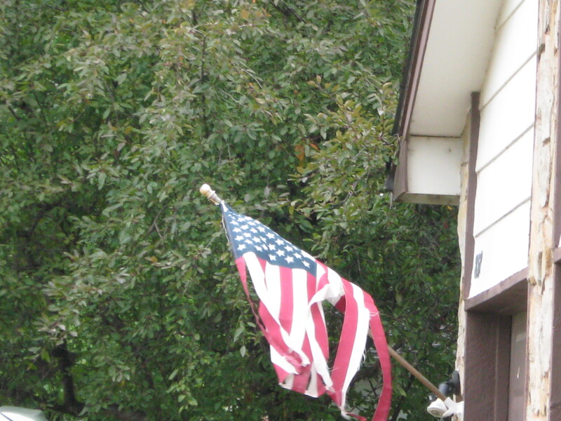 A shredded flag flying outside a house.