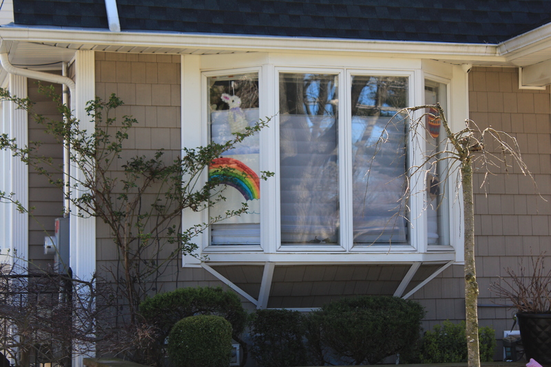 A residential house with a rainbow on a window.