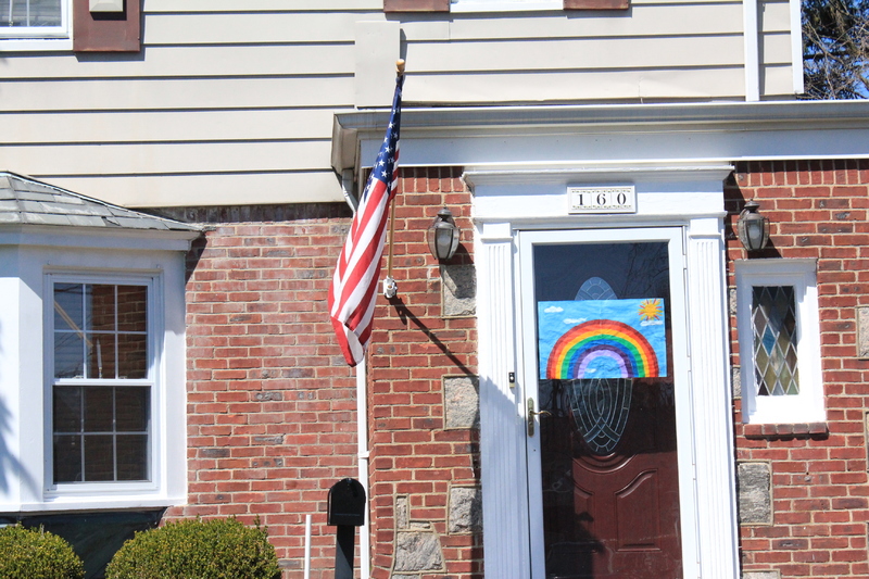 A residential house with a rainbow on the front screen door.