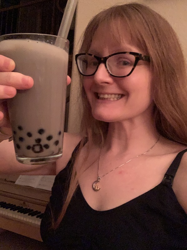 This is a picture of a smiling woman holding a glass of fresh bubble tea. 
