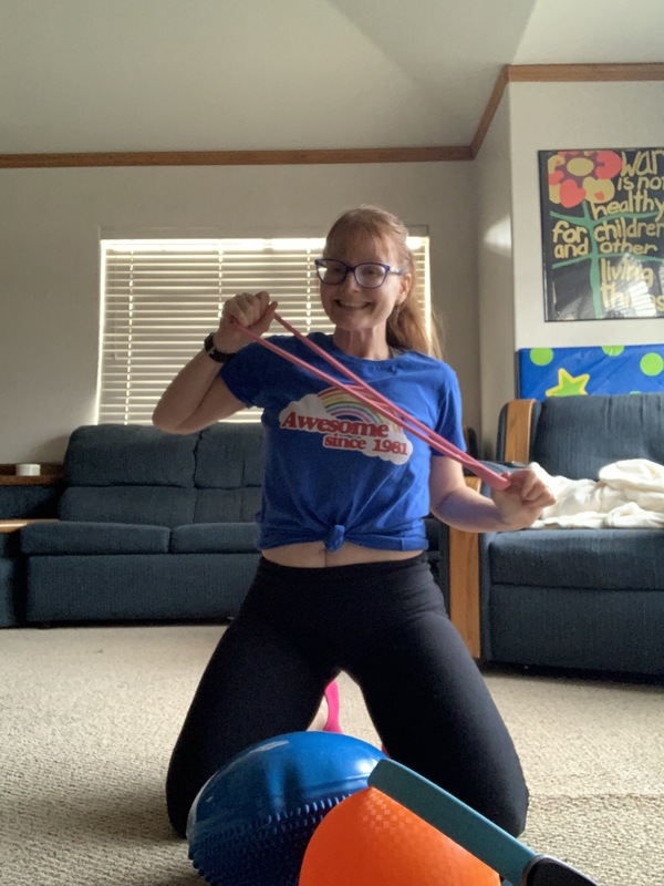 Photo of a woman smiling and stretching out an exercise band.