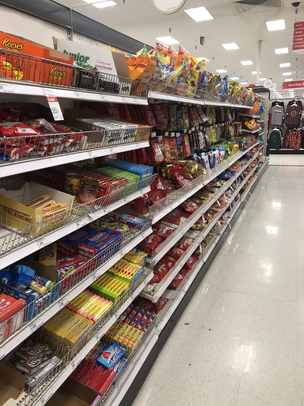 An isle in a store with rows of fully stocked candy. 