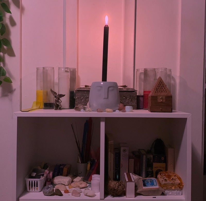 This is a picture of a person's bookshelf, which is decorated with different types of candles and various rocks. 