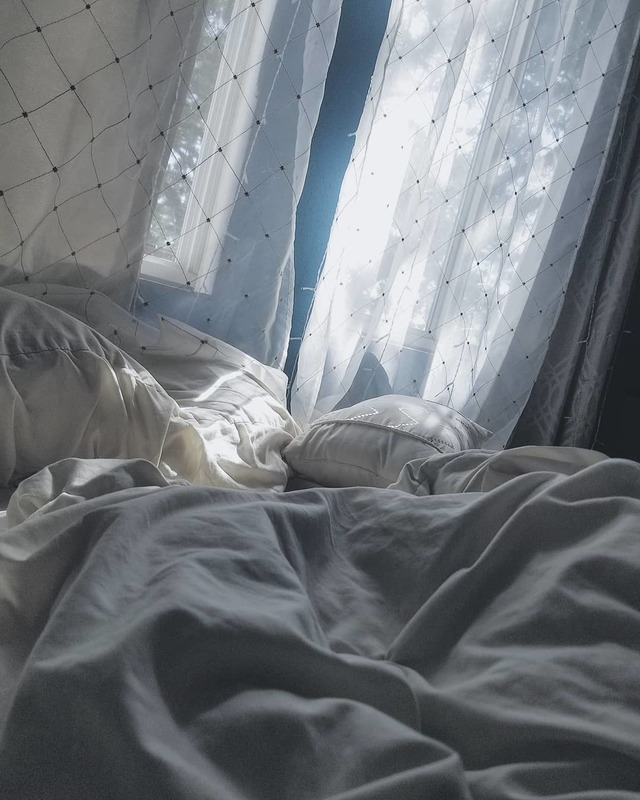 an unmade bed with gray comforter and white pillows 