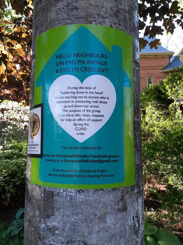 This is a picture taken of a green flyer posted on a light pole which reads: "Hello neighbors on Evelyn Avenue & Evelyn Crescent! During this time of 'hunkering down in the hood' we are reaching out to anyone who is interested in connecting with those up and down our street. The purpose of the group is to share info, ideas, requests for help or offers of support during the COVID crisis. You can get connected by: joining the EveryoneOnEvelyn facebook group or, emailing us at EveryoneOnEvelyn@gmail.com. From the corner of Evelyn & Evelyn- we are looking forward to hearing from you!". 