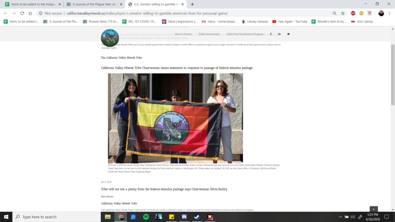 Three people holding up a tribe's flag. 