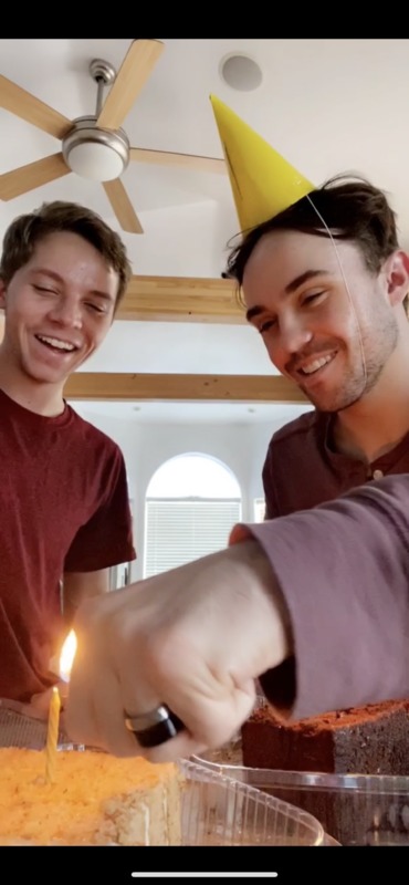 Two people lighting a birthday cake. 