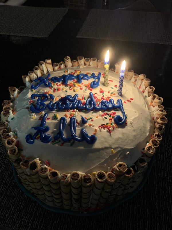 A birthday cake covered in frosting with lit candles. 
