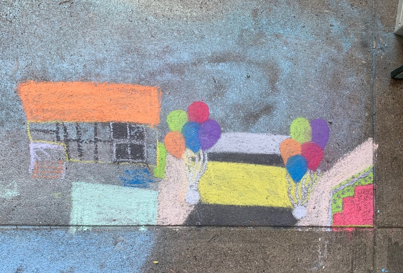 Photo of a chalk drawing on the sidewalk of balloons and buildings.