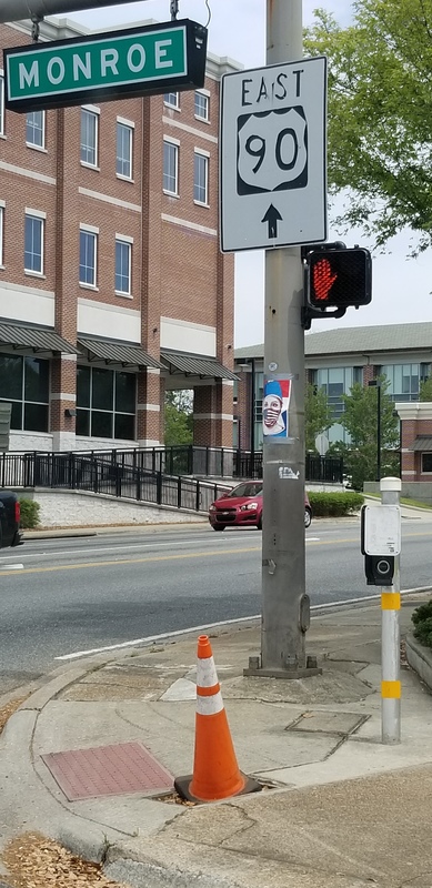 A poster taped on a stoplight pole that has a healthcare worker wearing an American flag face mask. 