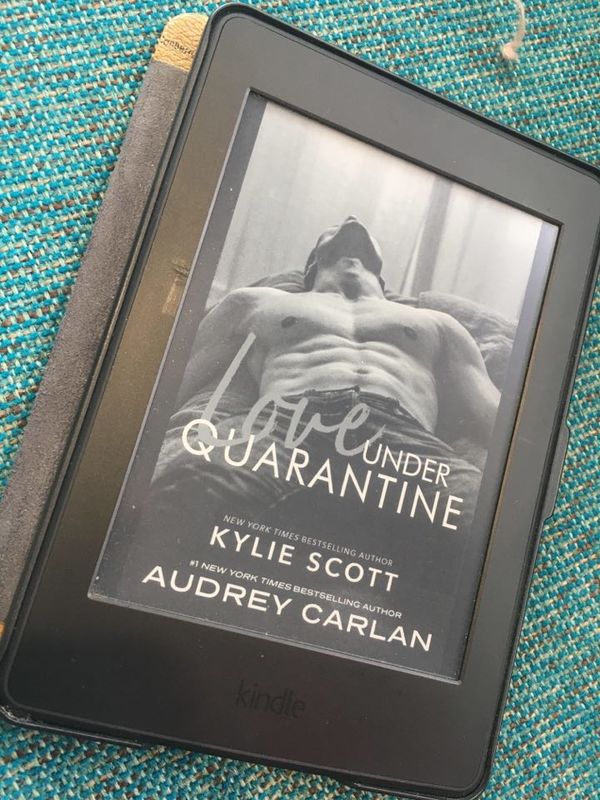 Black Amazon Kindle displaying book cover for "Love Under Quarantine" by Kylie Scott and Audrey Carlan. 