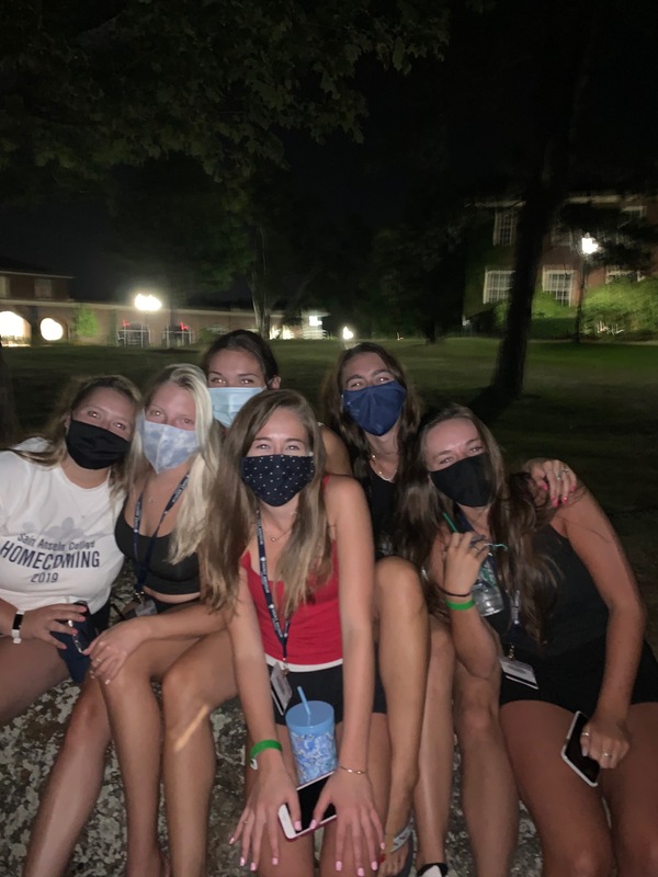 This is a picture of a group of six women wearing face masks, who are posing and smiling for the camera in an outdoor setting. 