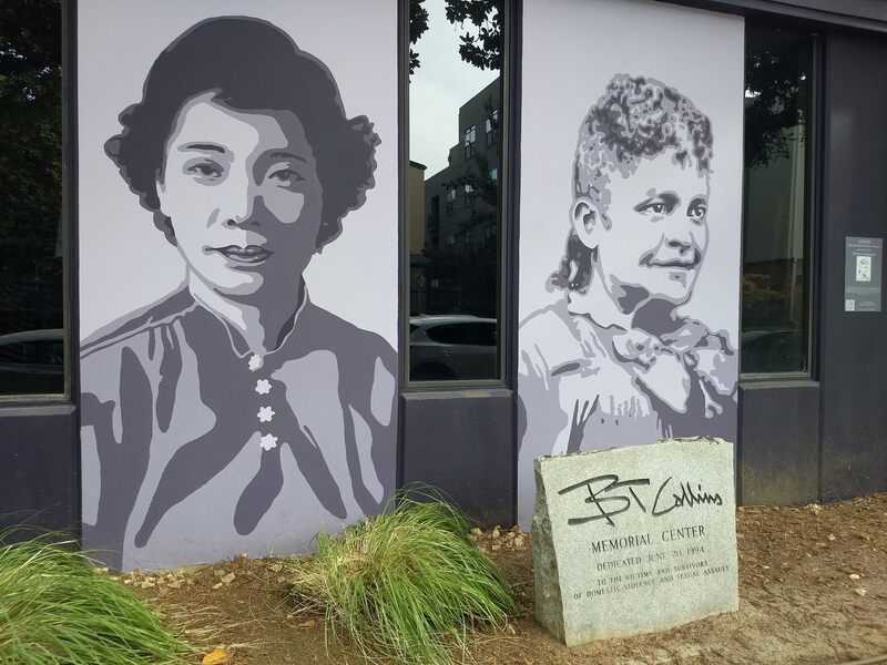 This is a picture taken of a series of murals that are painted on the side of a building. Two women in different periods of clothing are depicted in black and white. 