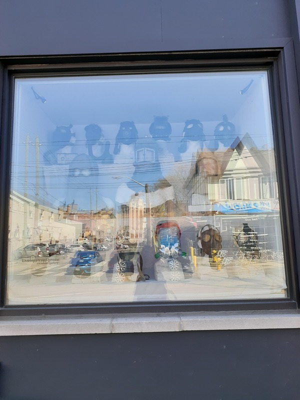 This is a picture taken of a display of gas masks for sale behind a glass storefront window. 